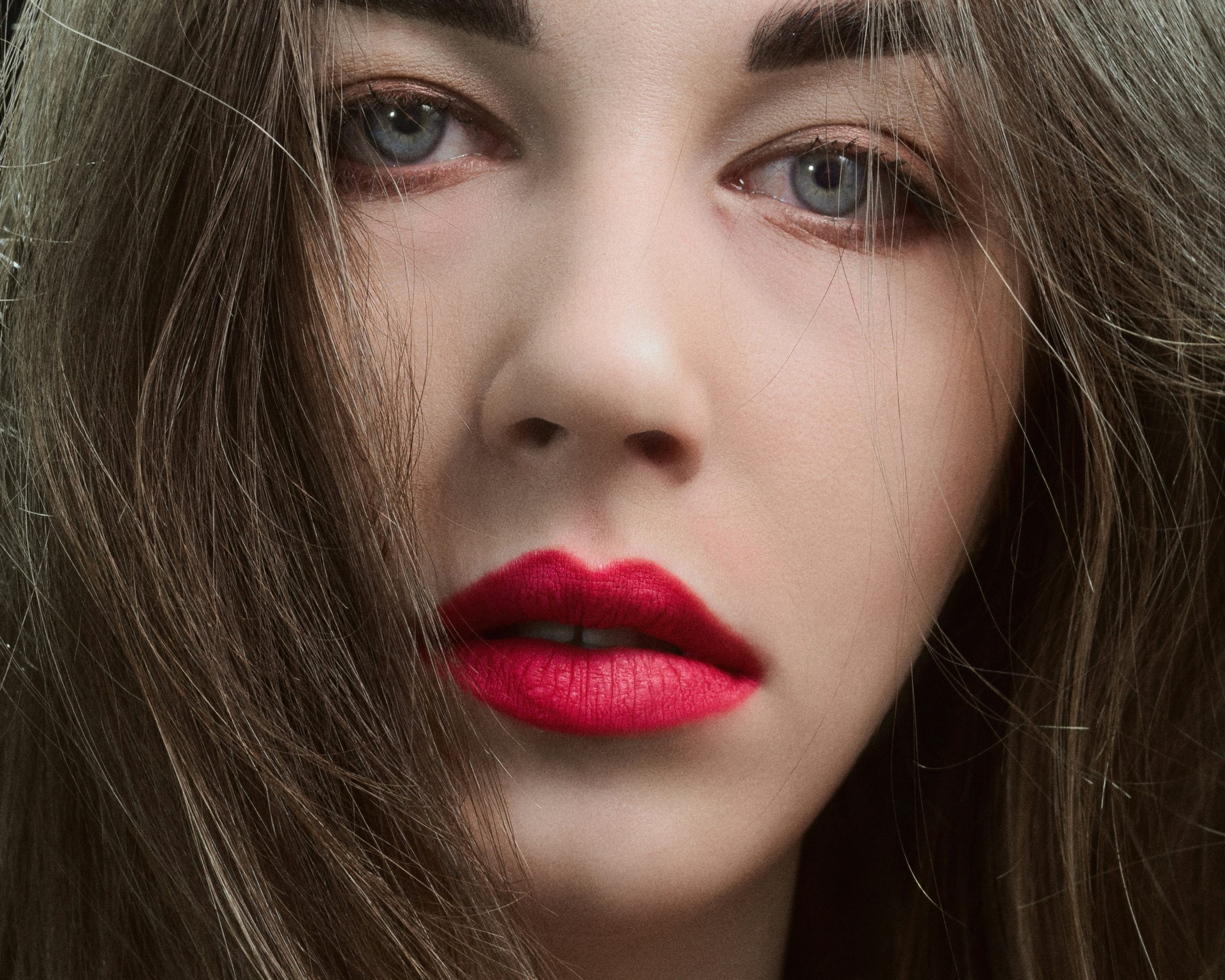 A model wearing dramatic red lipstick and smoky eye makeup inspired by fashion editorials