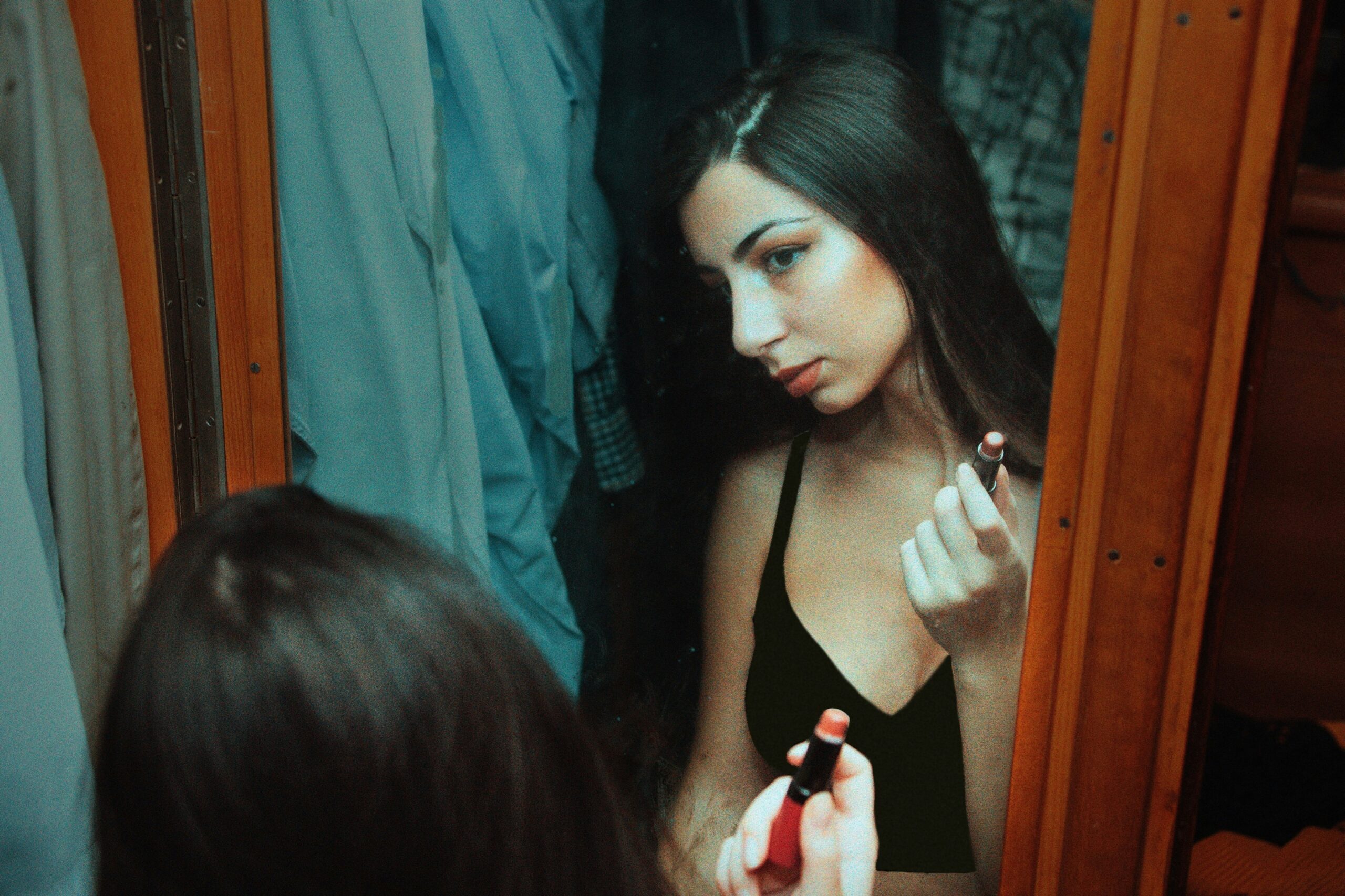 Makeup artist holding brushes next to product palette and mirrors