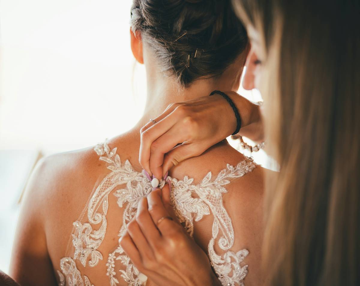 A close shot of a makeup artist misting setting spray onto a bride’s face post-makeup application.