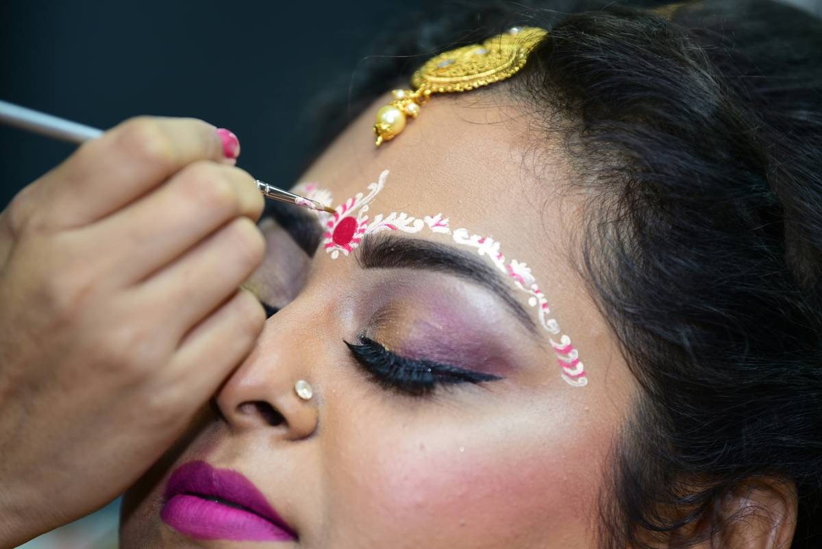 A makeup artist gently applying primer to a model's face using circular motions.