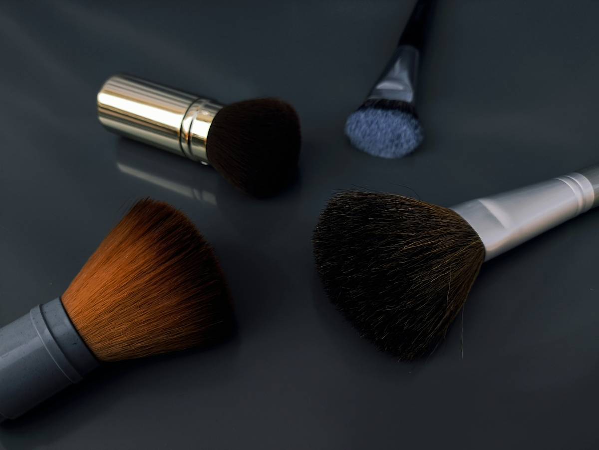 A makeup artist holding brushes and palettes ready for application.